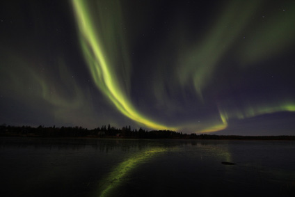 Die grnen Lichter spiegeln sich in der klaren Eisschicht auf dem See.